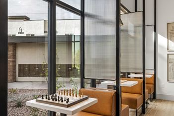 A chess board is set up on a table in front of a glass wall.